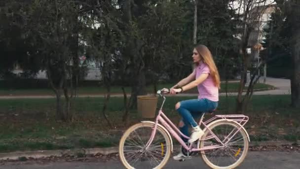 Menina ruiva bonita gengibre andando de bicicleta com cesta na rua no parque da cidade de verão — Vídeo de Stock