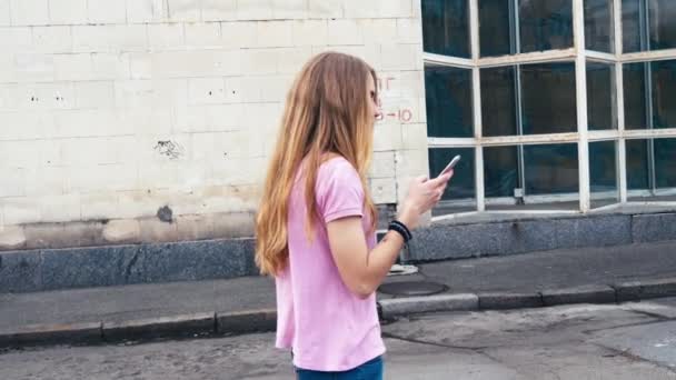 Руда імбирна жінка використовує мобільний телефон під час прогулянки по вулицях міста — стокове відео