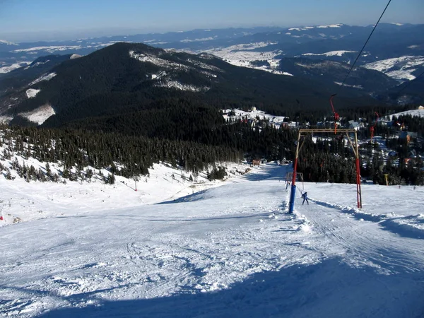 Un skieur monte aux remontées mécaniques, sur la route enneigée, dans le — Photo