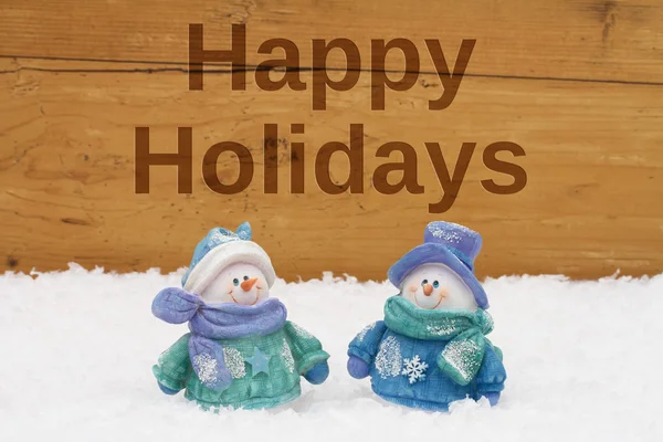 Happy Holidays Greeting,  Snowmen on snow with weathered wood ba — Stock Photo, Image