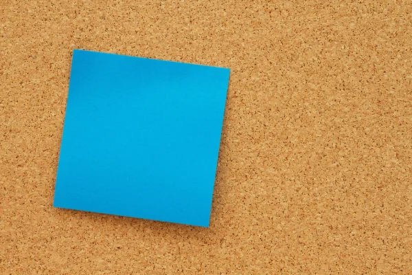 Tablón de anuncios con una nota adhesiva azul en blanco —  Fotos de Stock