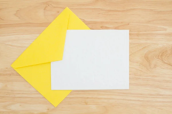 Eine geprägte weiße Karte mit gelbem Umschlag auf dem Schreibtisch — Stockfoto