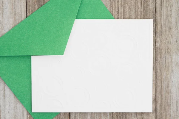 An embossed blank white card with green envelope on weathered wo — Stock Photo, Image