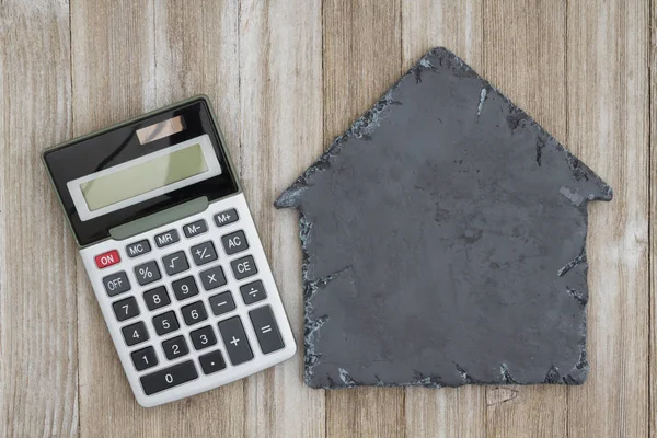 House shaped chalkboard with calculator on weathered wood — Stock Photo, Image