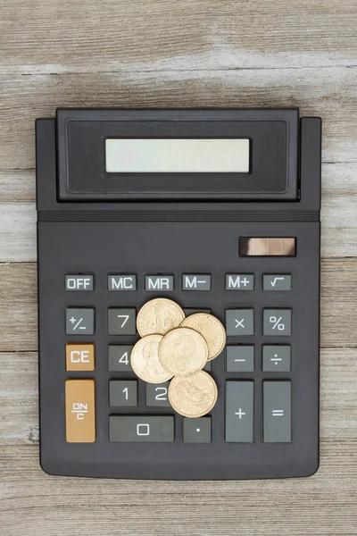 Calculator with a gold dollar coin on weathered wood — Stock Photo, Image