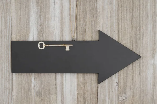 Freccia lavagna segno con una chiave scheletro su legno intemperie — Foto Stock