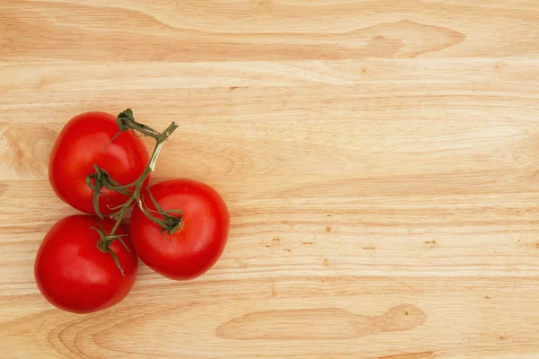 Tomates vermelhos maduros de videira em fundo de madeira — Fotografia de Stock