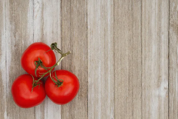 Yıpranmış ahşap arka plan üzerinde kırmızı asma olgun domates