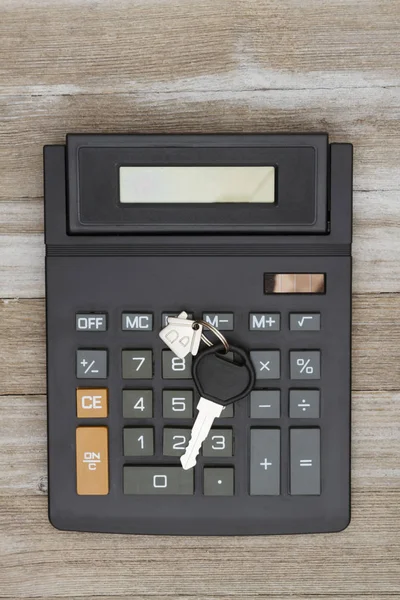 Calculator with house key on weathered wood — Stock Photo, Image
