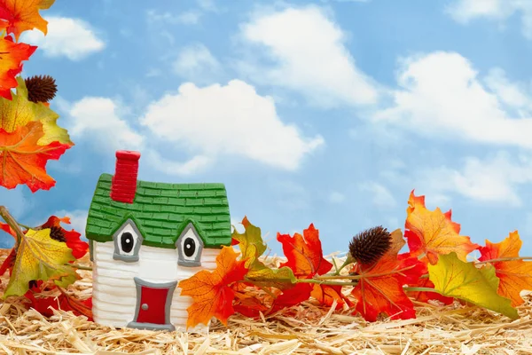 Дружелюбный дом и осенние листья на соломенном сене с небом — стоковое фото