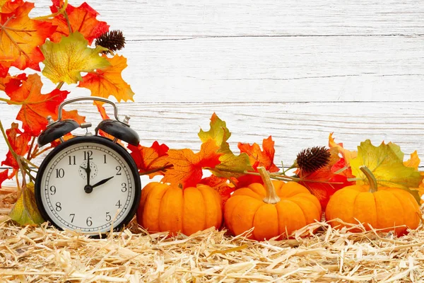 Scena di autunno con sveglia e zucche arancioni e caduta le — Foto Stock