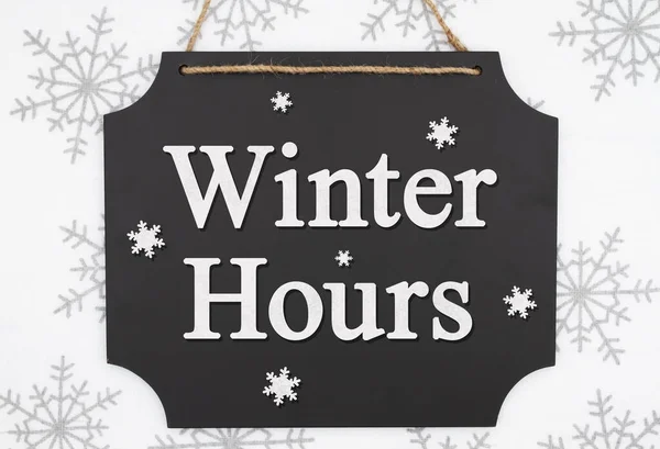 Winter Hours message on a retro hanging chalkboard with snowflak — ストック写真