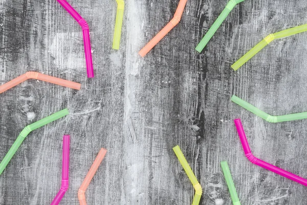 Multi gekleurde plastic rietjes op zwarte grunge achtergrond — Stockfoto