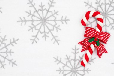 Gri ve beyaz kar taneleri üzerinde kırmızı şeker kamışı ya da Noel b