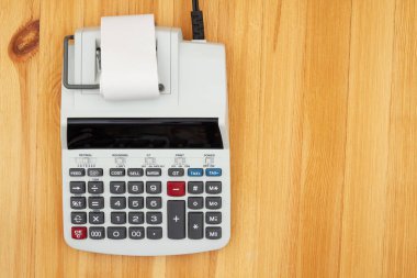 Tahta masasında ekranı olan elektrikli hesap makinesi.