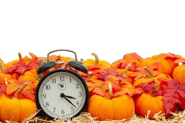 Reloj despertador retro con calabazas naranjas con hojas de otoño sobre paja — Foto de Stock