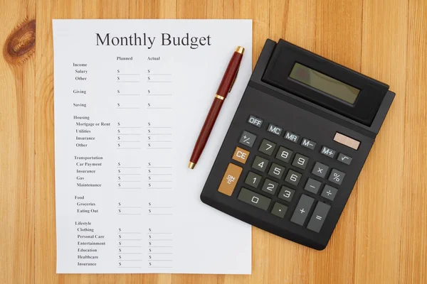 Creating your monthly budget with a calculator and pen — Stockfoto