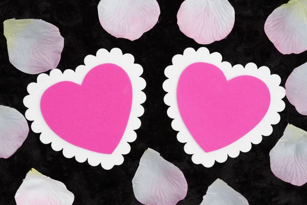 Two blank white and pink hearts on black rose textured plush fab — Stockfoto