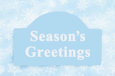 Mevsimin selamları mavi kar taneli bir tahta tabelanın üzerinde.