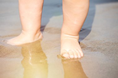 Gün batımında sahilde kum ile oynarken Bebe ayak kapatın