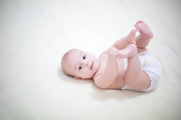 Menino brinca com os pés na cama depois de um banho — Fotografia de Stock