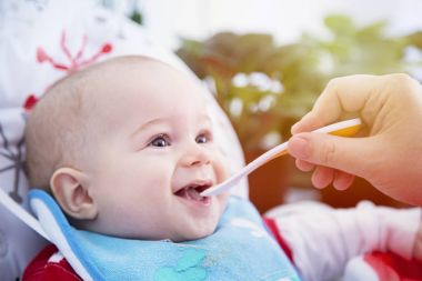 Bir çocuk yemek masasında kaşıkla