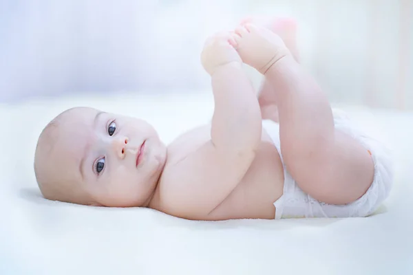 Lustiger kleiner Junge mit Windel, der auf einer weißen Decke spielt — Stockfoto