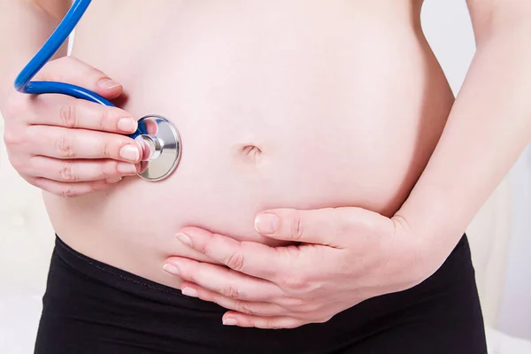 Immagine di donna incinta con lo stetoscopio sulla pancia ascoltare — Foto Stock