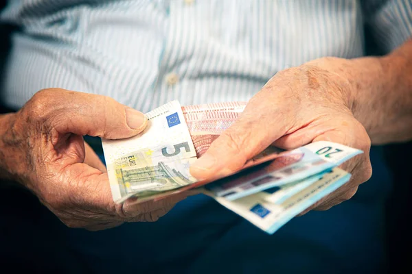 Yaşlı adam evde oturup onun parasını sayıyor.