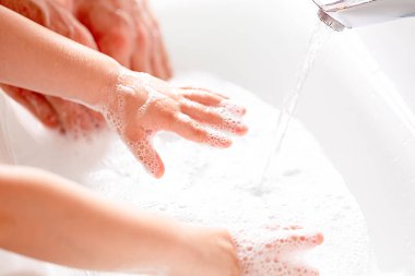 Küçük bir çocuk muslukta ellerini sabunla yıkıyor. Coronavirus önleme önlemleri. Hijyen, covid-19 yaymayı durdurmak için. Fotokopi alanı ile yakın çekim. Yumuşak odaklanma. El dezenfektanı