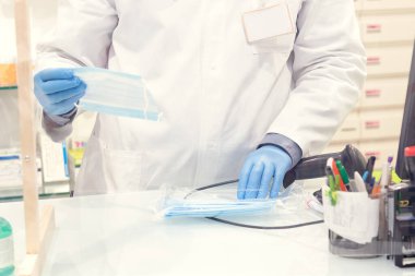 Eczanede alışveriş yapan biri. Eczacı koruyucu maskeler satıyor. Farmasinin bulanık arkaplanı. Enfeksiyondan covid-19 'a kadar koruyucu önlemler.
