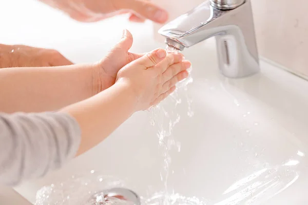 Küçük bir çocuk muslukta ellerini sabunla yıkıyor. Coronavirus önleme önlemleri. Hijyen, covid-19 yaymayı durdurmak için. Yumuşak odaklanma. El dezenfektanı