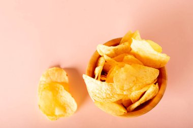 Pastel renkli bir masada, kasede çıtır patates cipsi olan atıştırmalıklar. Fast food konsepti. Kopyalama alanı olan düz alan,