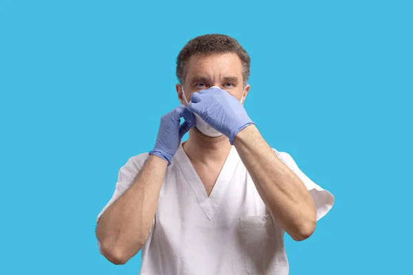 Surgeon prepares to enter the operating room during the coronavirus period, wearing personal protective equipment. Medical gloves, mask and glasses. Blue backgraund. Banner with copyspace for text.