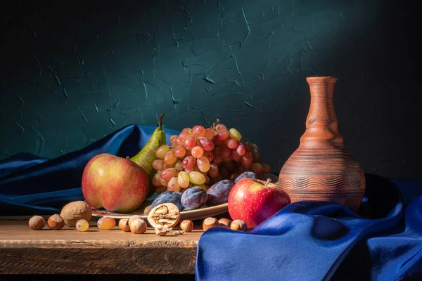 Bodegón con fruta y vino tinto. Uvas, manzanas, pera, ciruelas, frutos secos y cortinas azules —  Fotos de Stock