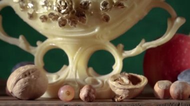 El yapımı kil testisi, vazoda üzümler, erikler, elmalar, fındıklar, armutlar ve bir bardak şarapla hayat.