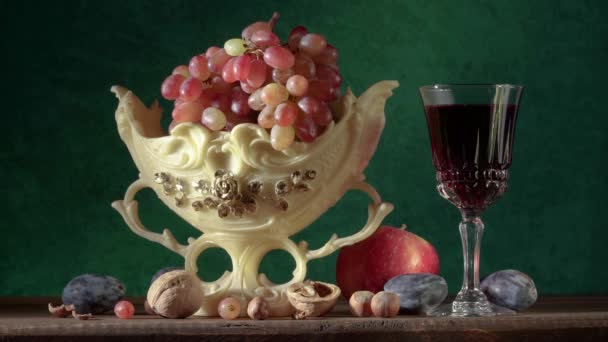 Zátiší s ručně vyráběným hliněným džbánem, hrozny ve váze, švestkami, jablky, ořechy, hruškami a sklenicí vína
