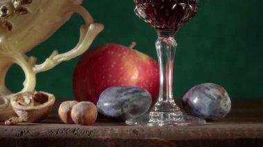 El yapımı kil testisi, vazoda üzümler, erikler, elmalar, fındıklar, armutlar ve bir bardak şarapla hayat.