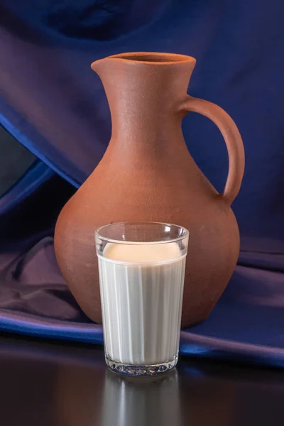 Ein Glas Milch und ein Tonkrug auf blauem Tuch — Stockfoto