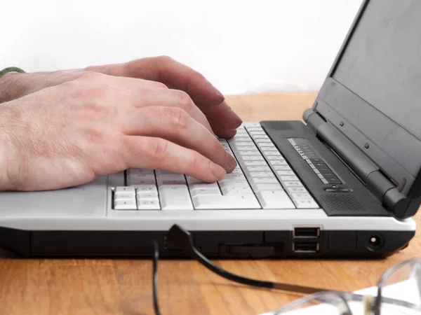 Eller dizüstü bilgisayarda yazıyor.