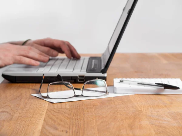 Eller dizüstü bilgisayarda yazıyor.