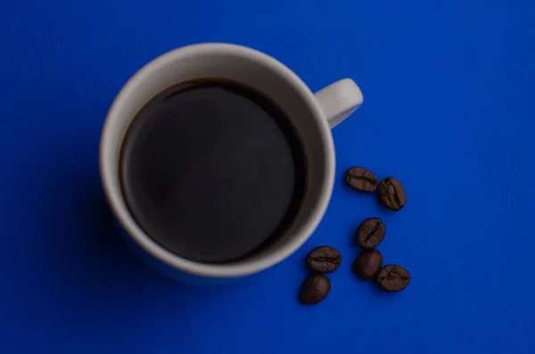 Filiżanka kawy espresso z ziaren kawy na niebieskim tle. Płaska, kreatywna konstrukcja. — Zdjęcie stockowe