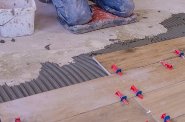 laying tile on the floor, ceramic tile laying, pressing down and regulating, installing plastic industrial crosses for fixing,