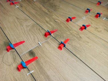 New tile floor home renovation project, large format ceramic tiles with wood texture, plastic levelers and a notched trowel for mortar.