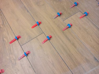 New tile floor home renovation project, large format ceramic tiles with wood texture, plastic levelers and a notched trowel for mortar.