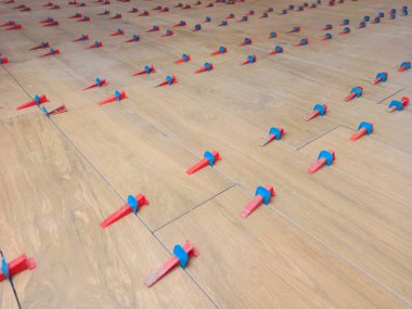 New tile floor home renovation project, large format ceramic tiles with wood texture, plastic levelers and a notched trowel for mortar.