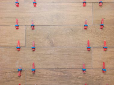 New tile floor home renovation project, large format ceramic tiles with wood texture, plastic levelers and a notched trowel for mortar.