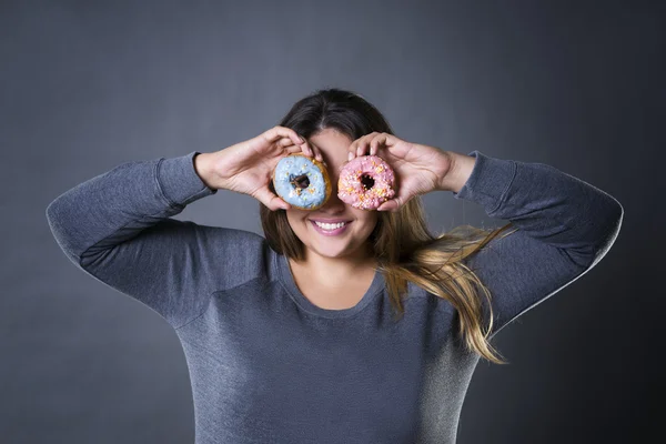 Feliz bonito jovem caucasiano plus size modelo posando com donuts em um fundo de estúdio cinza — Fotografia de Stock