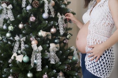 Genç hamile kadın Noel ağacı arka plan üzerinde poz