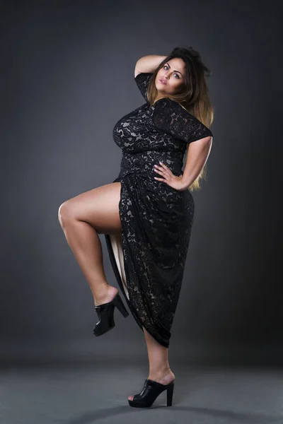 Giovane bella plus size modello in draghe nere, donna xxl su sfondo grigio studio — Foto Stock